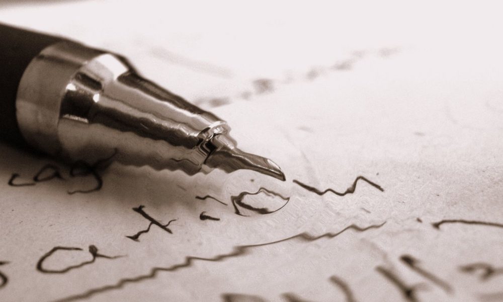 在特写镜头中，一支钢笔放在一张写着字的纸上。笔尖对焦了