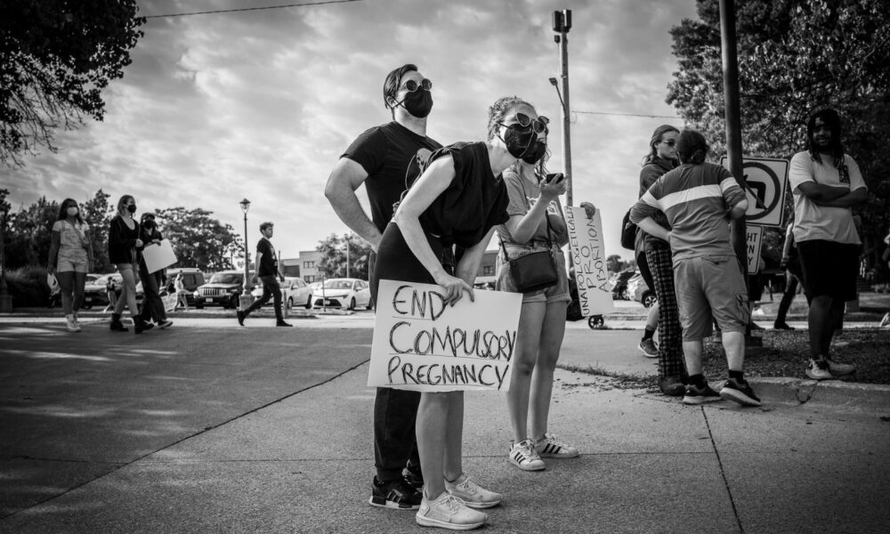 爱荷华州得梅因，一群人抗议最高法院推翻罗伊诉韦德案。一个人举着一个牌子，上面写着“终止强制怀孕”。