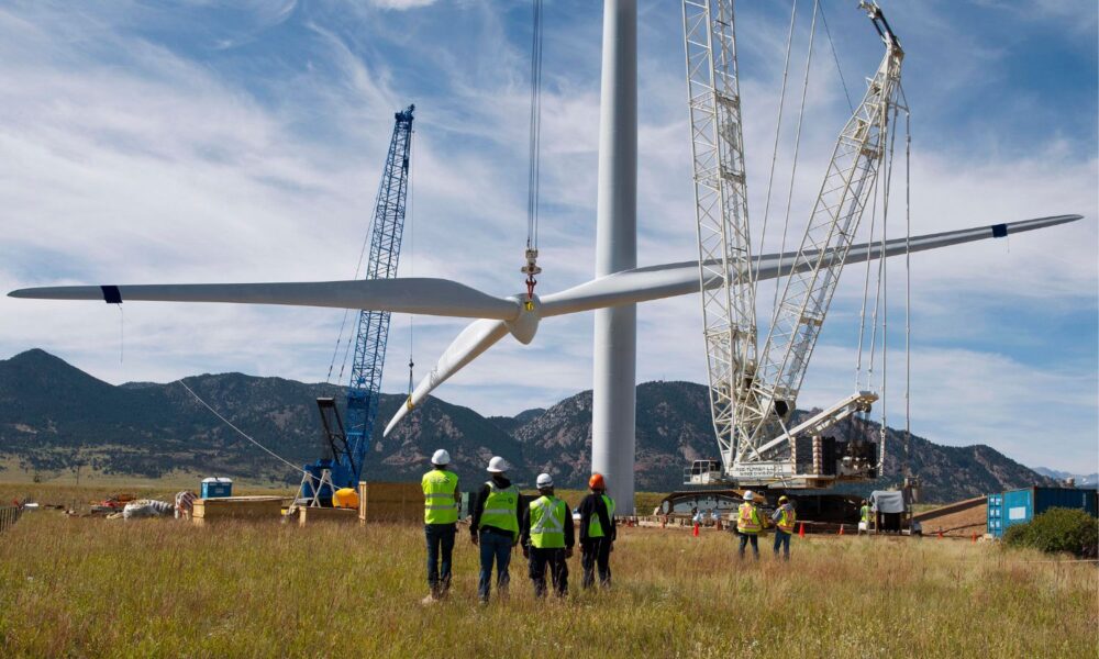 工人们在观看风力涡轮机叶片的安装。