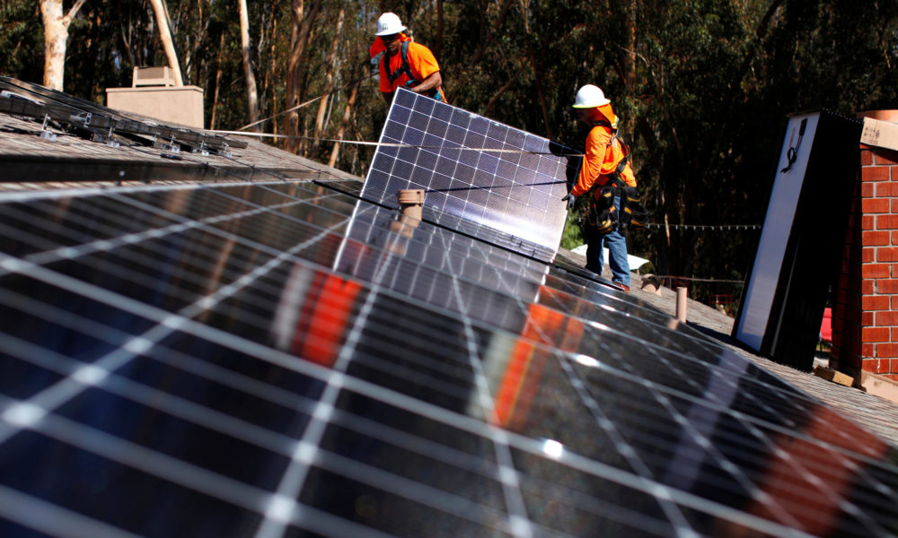 美国加利福尼亚州圣地亚哥斯克里普斯牧场，贝克电气公司的太阳能安装人员将太阳能电池板安装在住宅的屋顶上