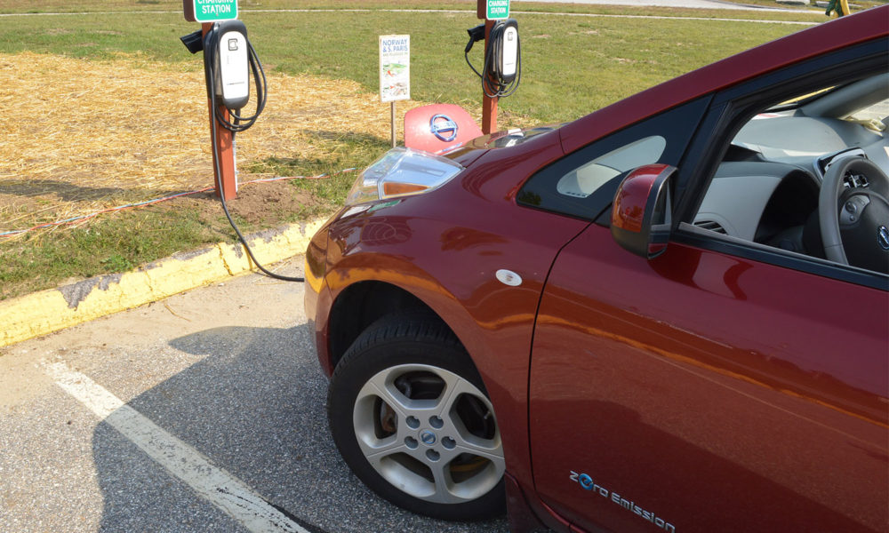 a red Nissan electric vehicle at a charging station