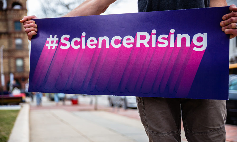 男子在城市街道上举着科学崛起的牌子