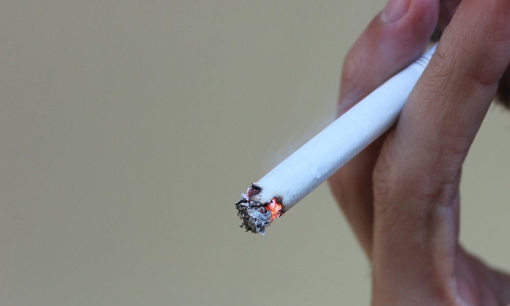 一个人手中点燃的香烟的特写视图