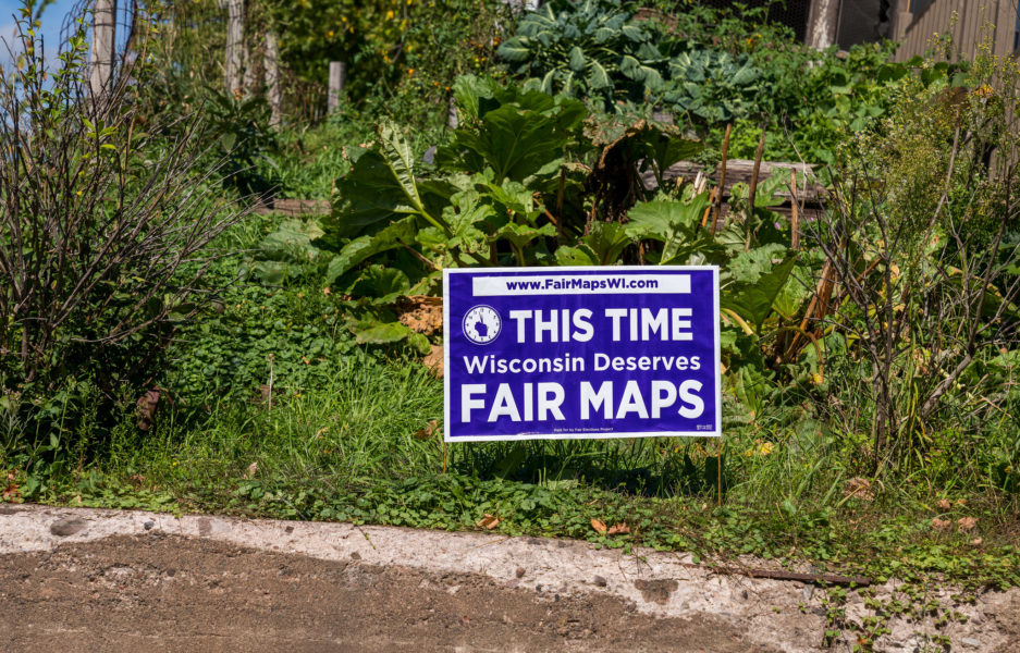 草坪上插着一个紫色的庭院标牌，上面写着:“这次威斯康辛州应该拥有公平的地图。”