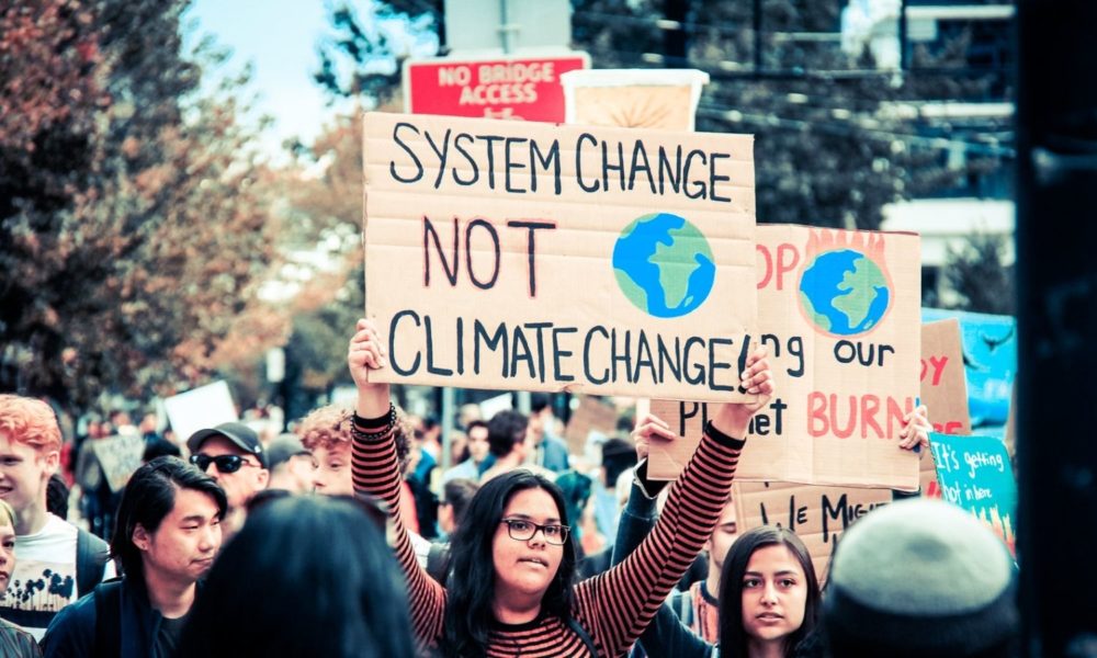 在加拿大温哥华举行的一场青年气候罢工游行中，一名年轻女子举着一个牌子，上面写着“改变制度，而不是气候变化”
