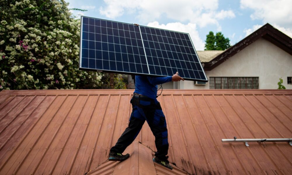 PHILERGY是一家德国-菲律宾太阳能供应商和安装商，一名工人在家庭安装过程中携带太阳能电池板。