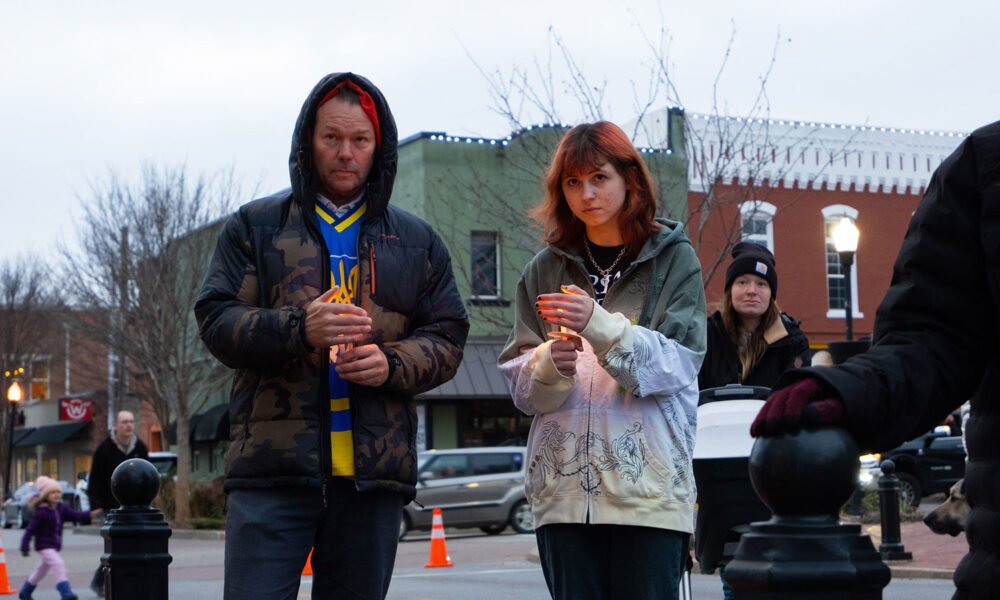 两个人举着蜡烛，参加乌克兰战争的守夜活动。