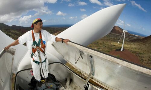 一个人站在110英尺高的风力涡轮机上。