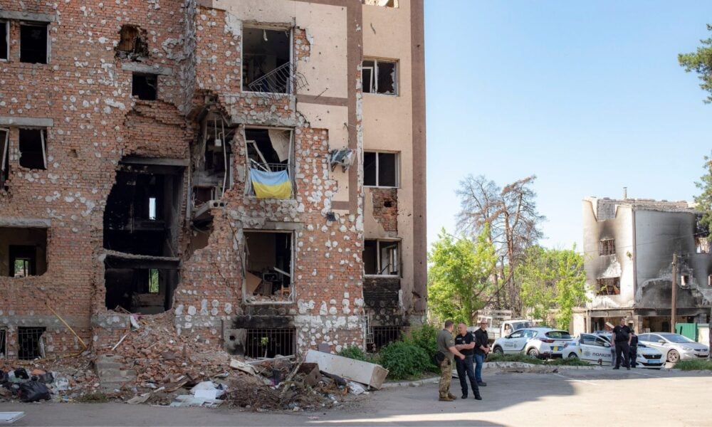 在乌克兰首都基辅，士兵们在一幢被炸毁的砖砌公寓楼前交谈，背景是另一栋被炸毁的建筑。
