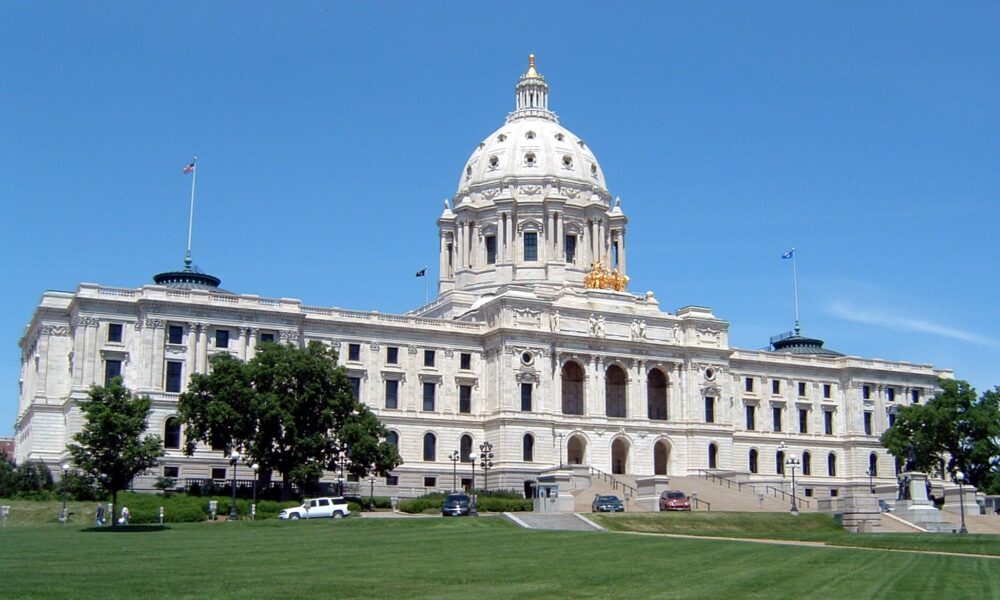 photo of the Minnesota State Capitol building, with trees and grass below and blue sky above