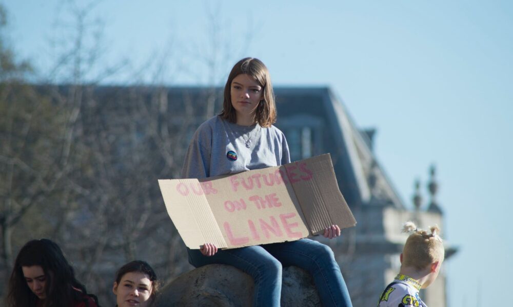 一名年轻人在抗议活动中举着“我们的未来悬于一线”的牌子