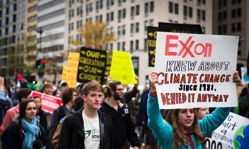 一名年轻的抗议者举着一个牌子，上面写着“埃克森美孚从1981年就知道气候变化，但还是否认了”。