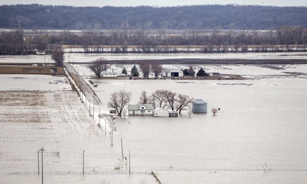被水淹没的农场航拍照片;水淹到了农舍和筒仓的侧面，房子旁边的一条路被淹没了