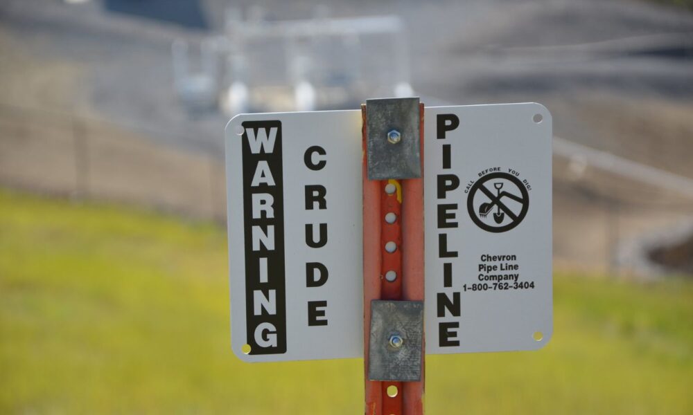 A sign reads WARNING CRUDE PIPELINE, against a background of grass in the Uinta-Wasatch-Cache National Forest in Utah and Wyoming